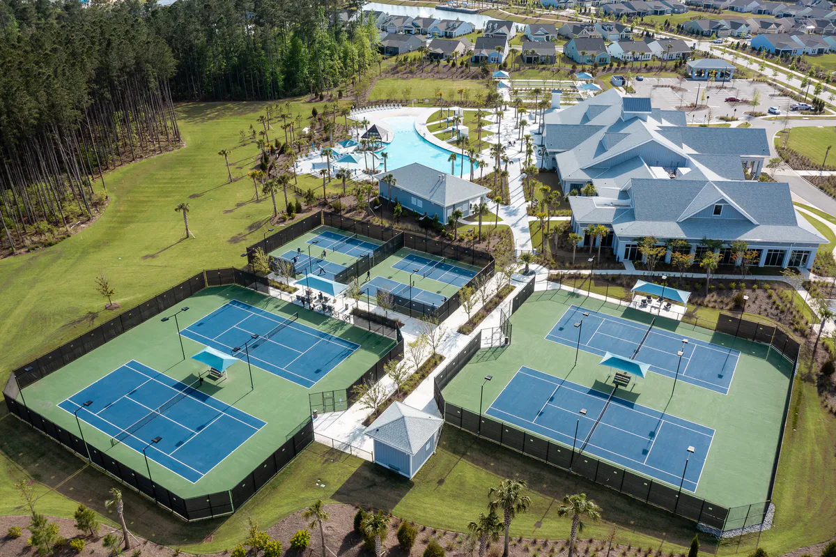 Aerial view of courts, a pool, clubhouse and homes at Del Webb Nexton